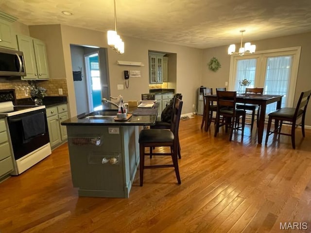 kitchen with range with electric stovetop, stainless steel microwave, a sink, a chandelier, and dark countertops