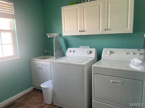 laundry room featuring washer and clothes dryer, cabinet space, and baseboards