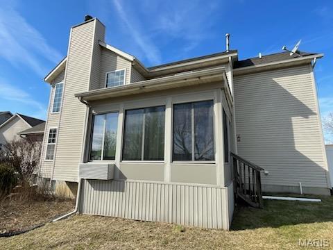 rear view of property with a sunroom and a chimney