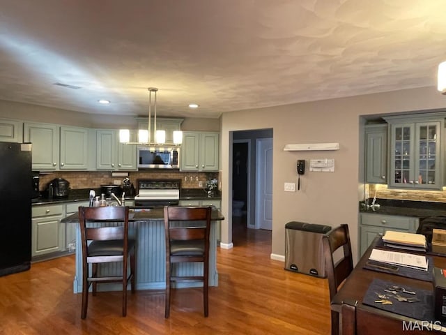 kitchen featuring stainless steel microwave, stove, freestanding refrigerator, dark countertops, and recessed lighting