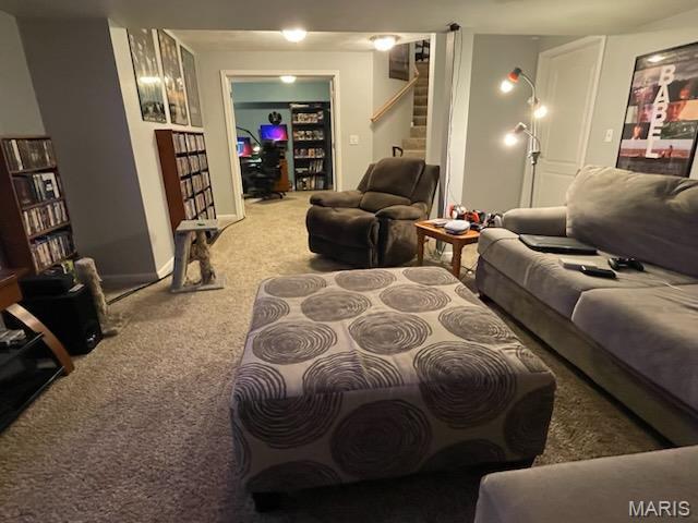carpeted living area featuring stairway and baseboards
