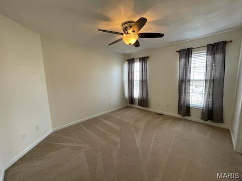 unfurnished room with a ceiling fan, light colored carpet, and baseboards