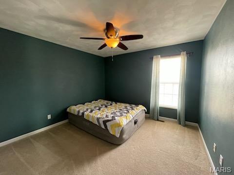 bedroom featuring light colored carpet, ceiling fan, and baseboards