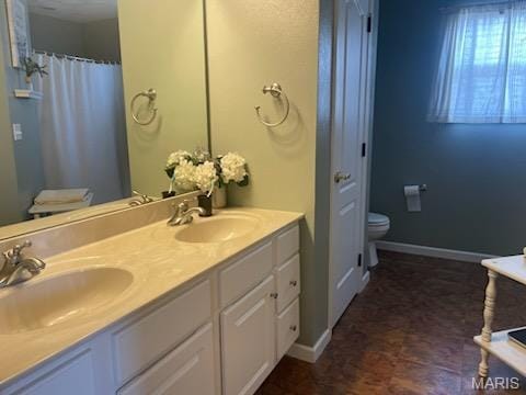 full bathroom featuring toilet, baseboards, and double vanity