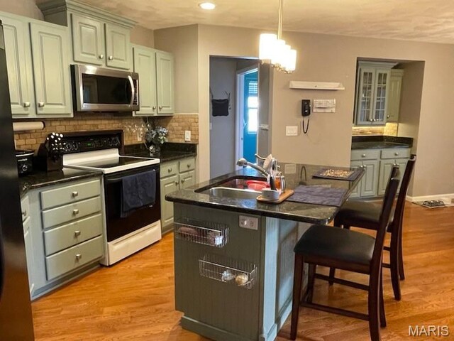 1212 Usher Dr, Ofallon, IL 62269 - kitchen with appliances with stainless steel finishes, dark countertops, a sink, backsplash, and a breakfast bar area