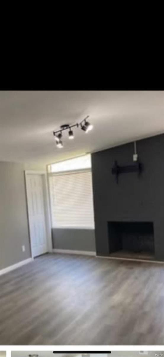 805 Derhake Rd, Florissant, MO 63033 - unfurnished living room with a fireplace, baseboards, and wood finished floors