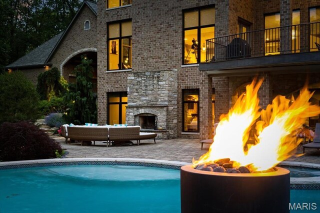 2535 S Lindbergh Blvd, Saint Louis, MO 63131 - back of property featuring an outdoor stone fireplace, a fire pit, a balcony, a patio area, and brick siding