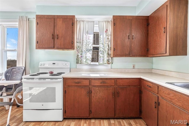 215 Virginia St, Saint Genevieve, MO 63670 - kitchen featuring white electric range, light wood-style flooring, light countertops, and brown cabinetry