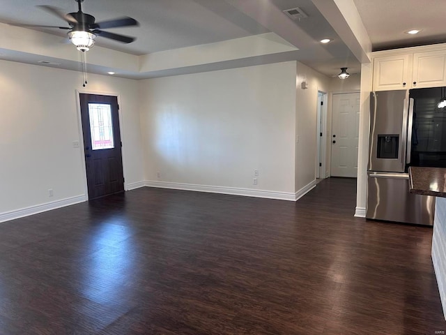 unfurnished living room with a ceiling fan, baseboards, dark wood-style floors, a tray ceiling, and recessed lighting