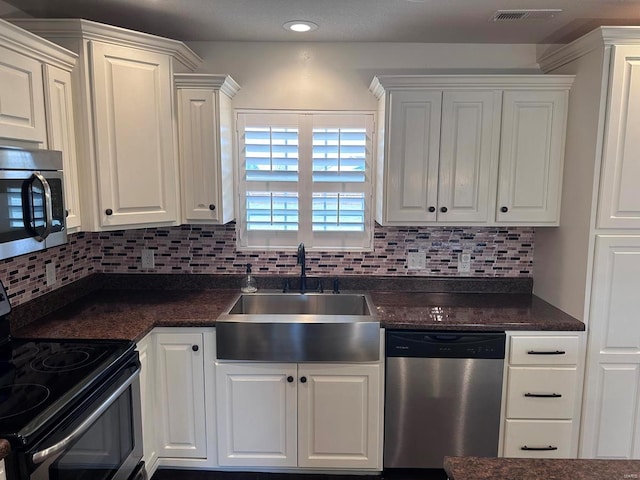 kitchen with stainless steel appliances, a sink, white cabinetry, dark countertops, and recessed lighting