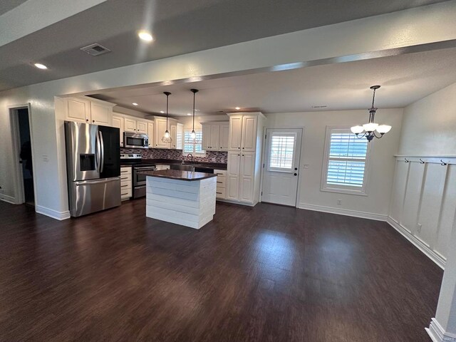 kitchen featuring stainless steel appliances, a chandelier, dark wood-style floors, dark countertops, and white cabinetry
