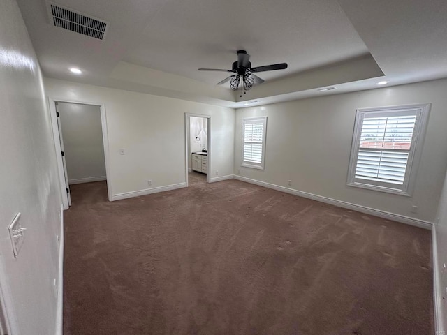 unfurnished bedroom featuring baseboards, a tray ceiling, carpet flooring, recessed lighting, and ensuite bathroom