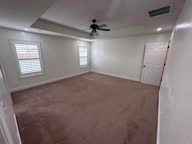 empty room with a tray ceiling, baseboards, carpet, and recessed lighting