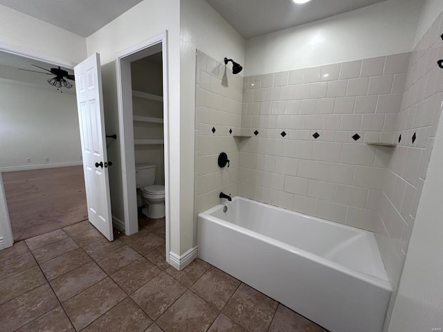 bathroom with a ceiling fan, toilet, baseboards, and shower / washtub combination