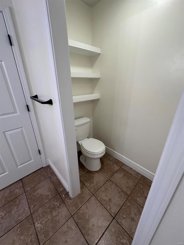 bathroom with toilet, baseboards, and tile patterned floors