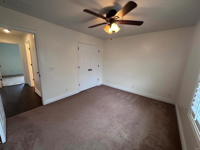 unfurnished bedroom featuring dark colored carpet, baseboards, and a ceiling fan