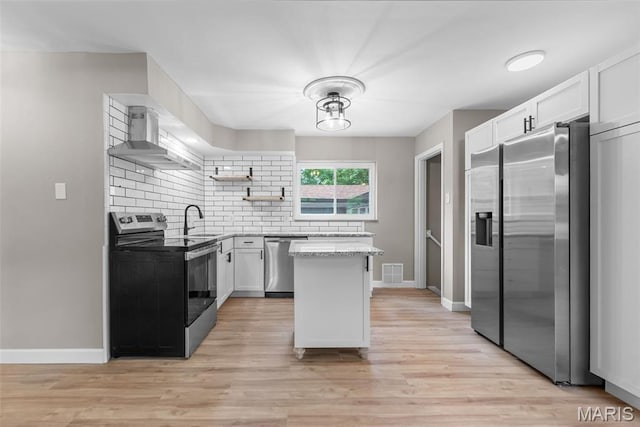 1247 Charlane Ct, Saint Louis, MO 63119 - kitchen featuring appliances with stainless steel finishes, open shelves, wall chimney range hood, decorative backsplash, and a center island