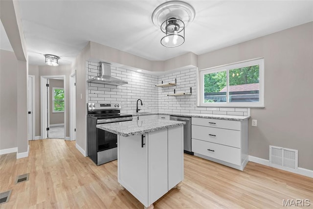 1247 Charlane Ct, Saint Louis, MO 63119 - kitchen with appliances with stainless steel finishes, wall chimney range hood, a kitchen island, decorative backsplash, and healthy amount of natural light