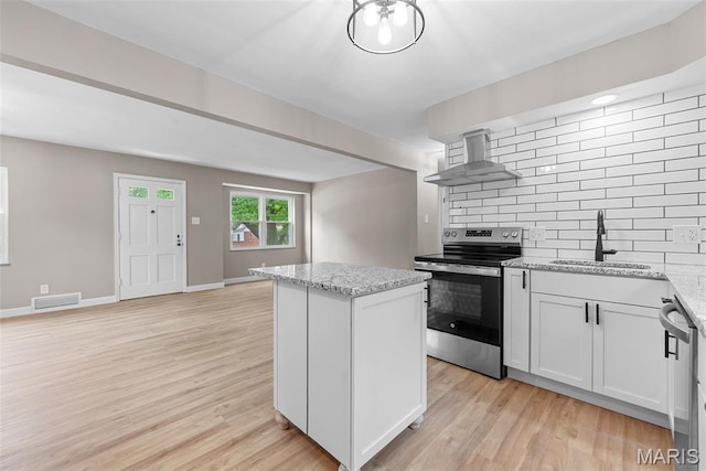 1247 Charlane Ct, Saint Louis, MO 63119 - kitchen featuring stainless steel appliances, wall chimney exhaust hood, tasteful backsplash, a kitchen island, and light wood-style floors
