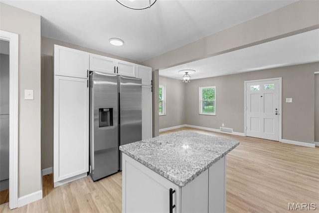 1247 Charlane Ct, Saint Louis, MO 63119 - kitchen with stainless steel fridge with ice dispenser, light wood-type flooring, a kitchen island, light stone counters, and white cabinets