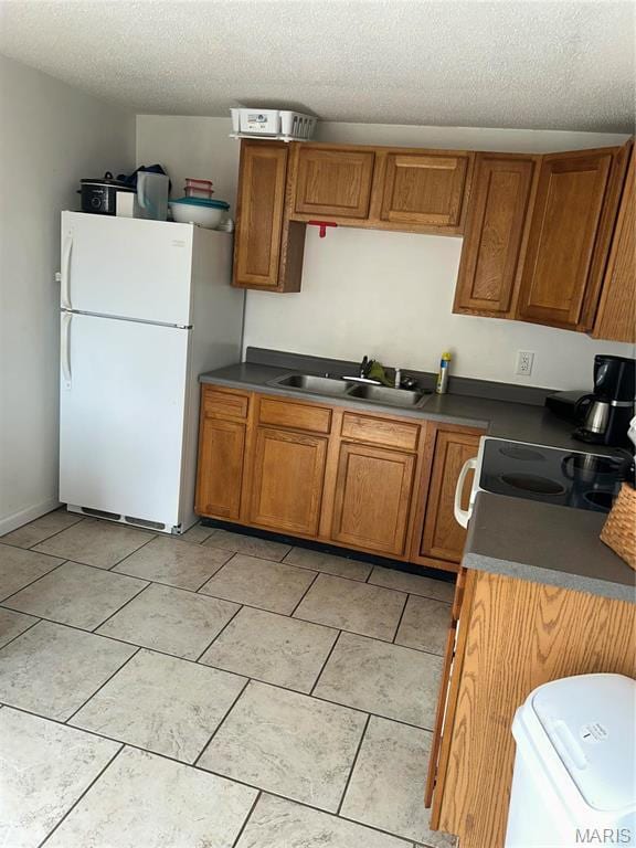 618 Church St, Hannibal, MO 63401 - kitchen featuring freestanding refrigerator, electric stove, brown cabinets, a textured ceiling, and dark countertops