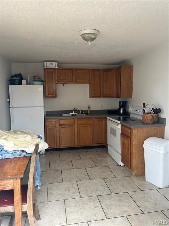 618 Church St, Hannibal, MO 63401 - kitchen featuring white appliances, brown cabinets, dark countertops, and a textured ceiling