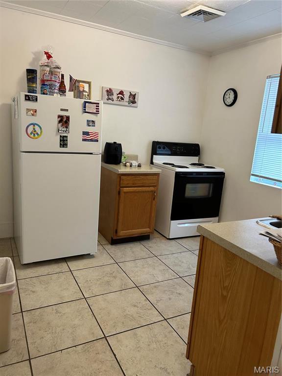 618 Church St, Hannibal, MO 63401 - kitchen with range with electric cooktop, freestanding refrigerator, light tile patterned flooring, ornamental molding, and light countertops