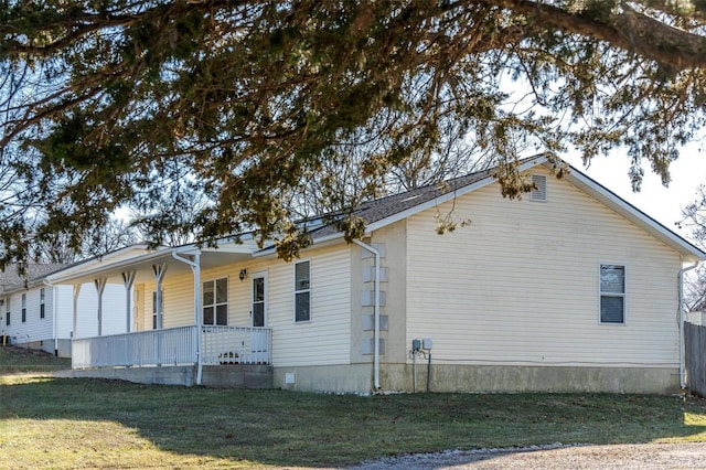 view of side of property featuring covered porch and a lawn