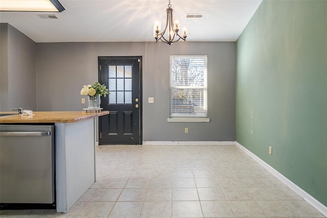 kitchen with stainless steel dishwasher, a chandelier, baseboards, decorative light fixtures, and light tile patterned floors