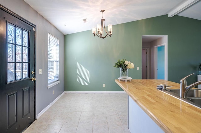 kitchen with a sink, a chandelier, butcher block counters, baseboards, and light tile patterned flooring