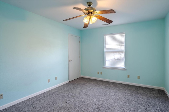carpeted spare room with ceiling fan and baseboards