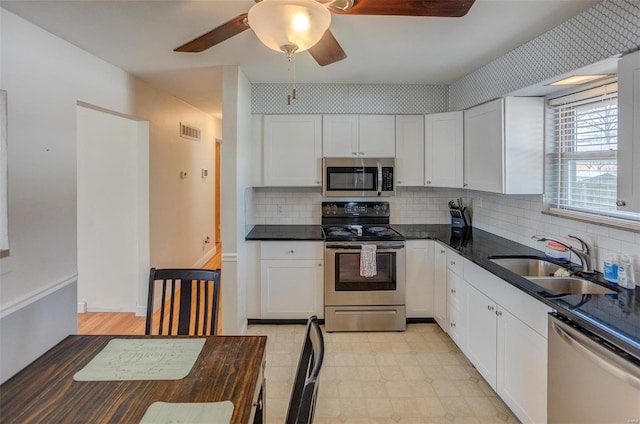 2571 Boyle Ave, Granite City, IL 62040 - kitchen with appliances with stainless steel finishes, a sink, dark countertops, ceiling fan, and light flooring