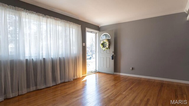 entrance foyer with ornamental molding, wood finished floors, and baseboards