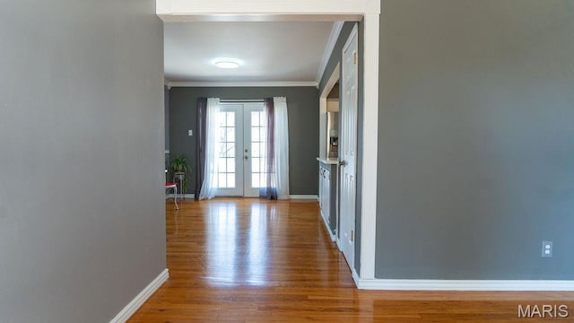 entryway with ornamental molding, wood finished floors, baseboards, and french doors