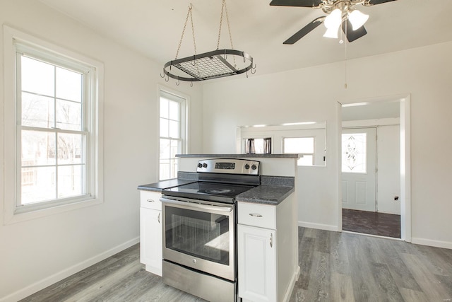 204 S Railroad St, Medora, IL 62063 - kitchen with stainless steel range with electric stovetop, dark countertops, light wood-style floors, and a ceiling fan