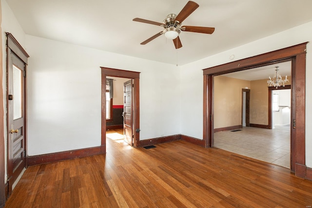204 S Railroad St, Medora, IL 62063 - empty room featuring wood finished floors, a chandelier, baseboards, and ceiling fan