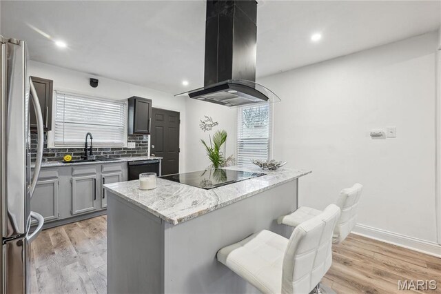 2808 Chadwick Dr, Bel-Nor, MO 63121 - kitchen featuring island exhaust hood, black appliances, backsplash, a sink, and light wood-type flooring