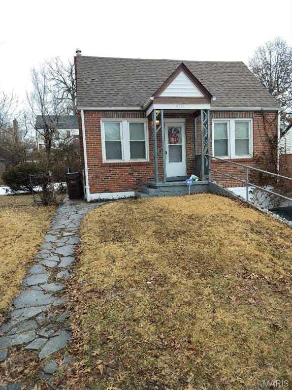 6711 Daiber St, Saint Louis, MO 63121 - bungalow featuring brick siding, roof with shingles, and a front yard