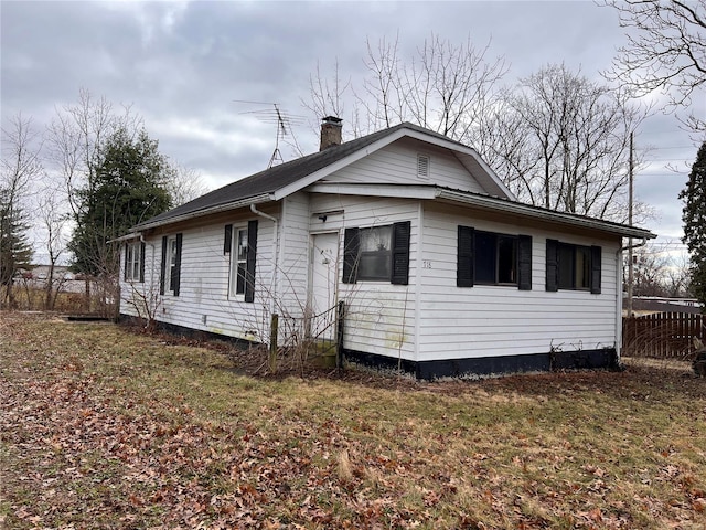 view of side of home featuring a chimney and fence