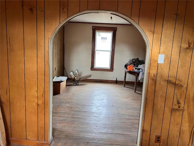additional living space featuring arched walkways, wood-type flooring, and wooden walls