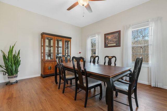 dining area with a ceiling fan, healthy amount of natural light, wood finished floors, and baseboards