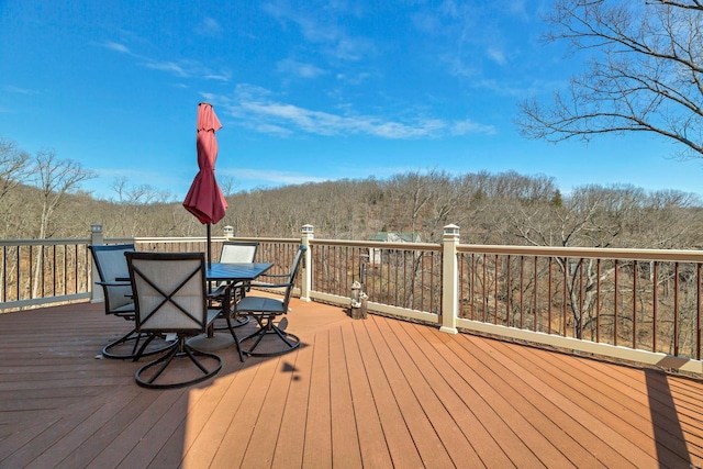 wooden terrace with outdoor dining area and a forest view