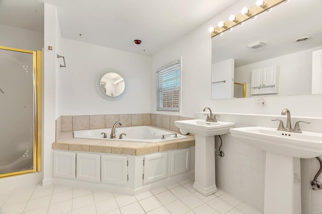 bathroom featuring a garden tub, tile patterned floors, a shower stall, and a sink