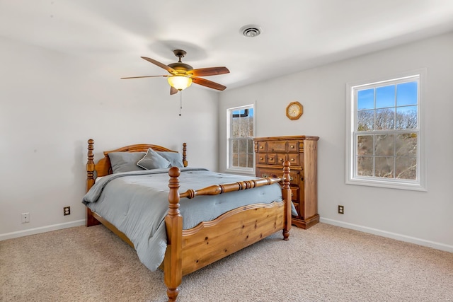 carpeted bedroom featuring baseboards, multiple windows, and a ceiling fan