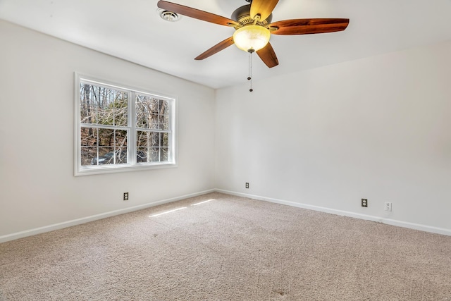 carpeted spare room featuring baseboards and a ceiling fan