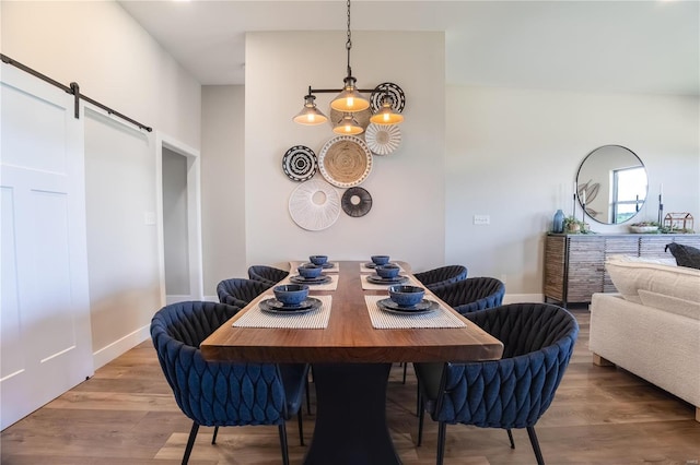 dining area featuring wood finished floors, baseboards, and a barn door