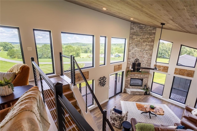 living area featuring vaulted ceiling, wood finished floors, wood ceiling, a stone fireplace, and recessed lighting
