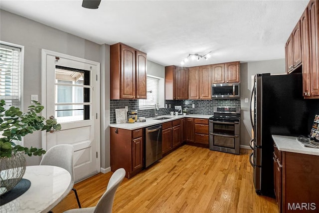 5816 Jamieson Ave, Saint Louis, MO 63109 - kitchen featuring stainless steel appliances, a sink, light wood-style floors, and tasteful backsplash