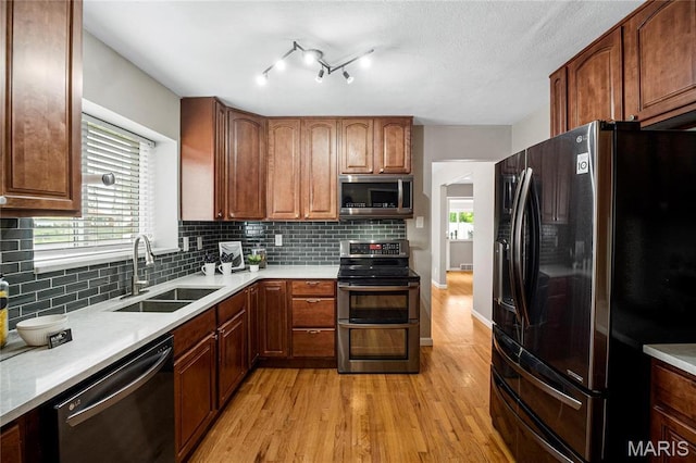 5816 Jamieson Ave, Saint Louis, MO 63109 - kitchen featuring stainless steel appliances, a sink, light wood-style flooring, and tasteful backsplash