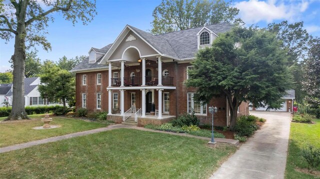 1011 N Ranney St, Sikeston, MO 63801 - greek revival house featuring a balcony, covered porch, brick siding, a front yard, and an outdoor structure